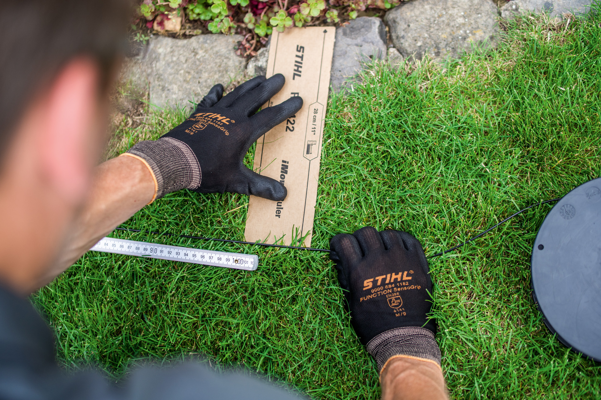 STIHL dealer laying perimeter wire for a STIHL iMOW robotic mower along a lawn edge